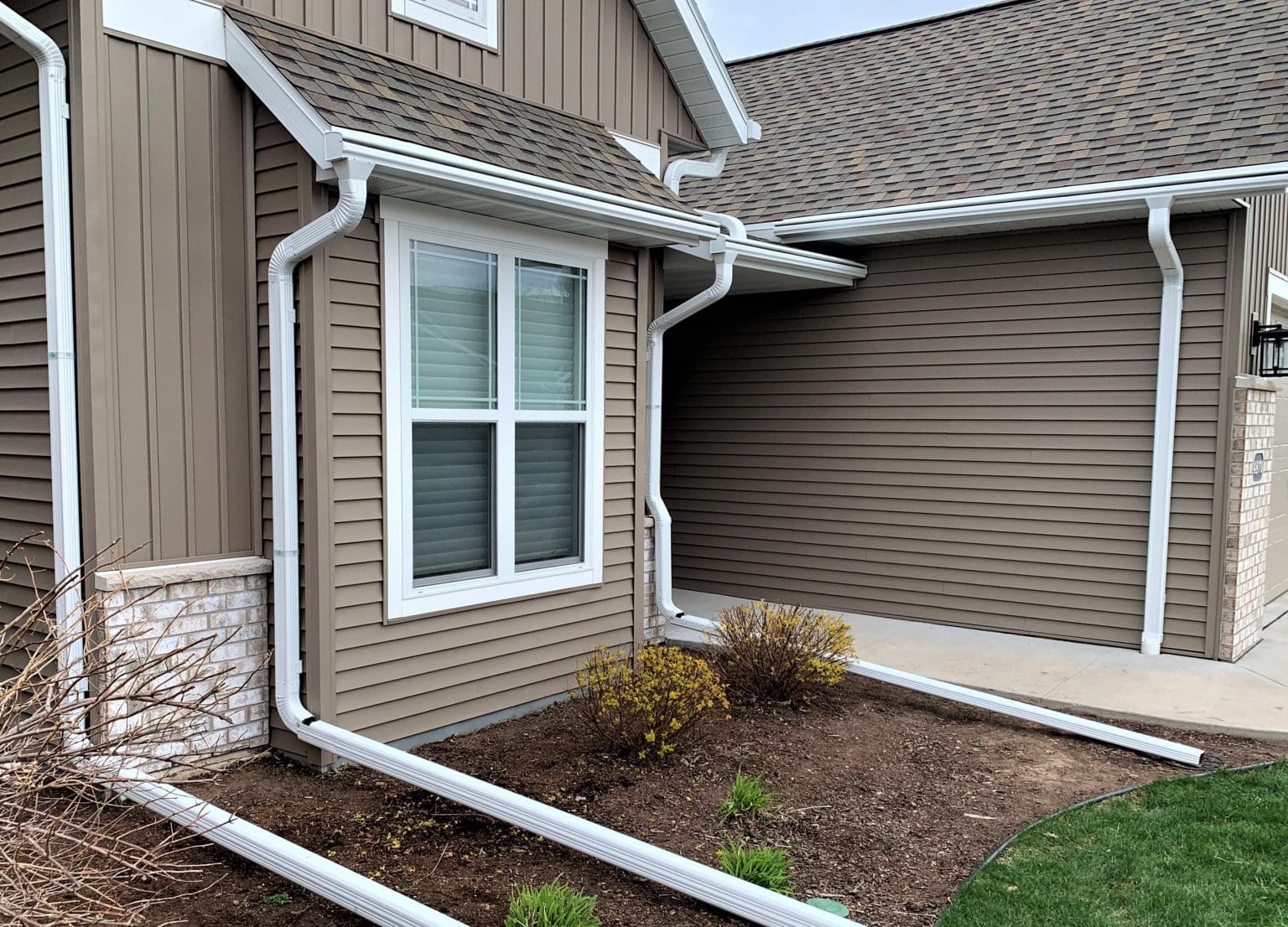 Completed brown siding, white gutters, and replacement windows